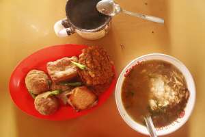 Semangkok soto segar dengan aneka gorengan dan secangkir kopi hitam